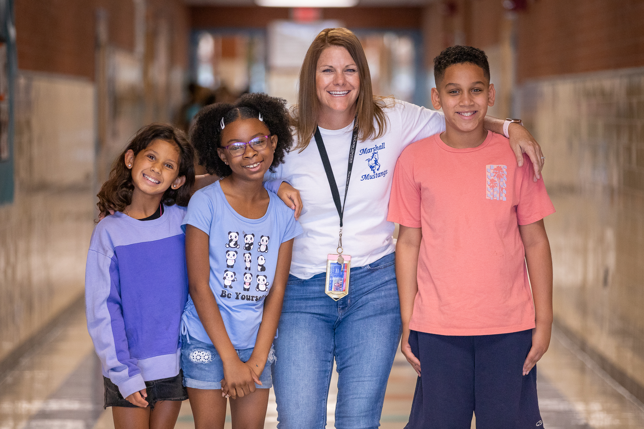 Three students smile and pose for a photo with Marshall's principal