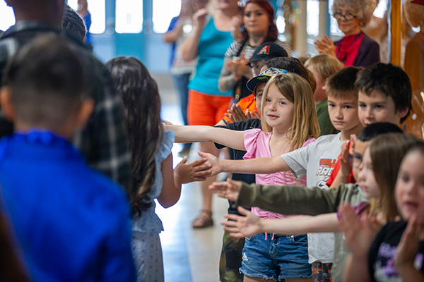 Younger students give high fives to 5th grade students