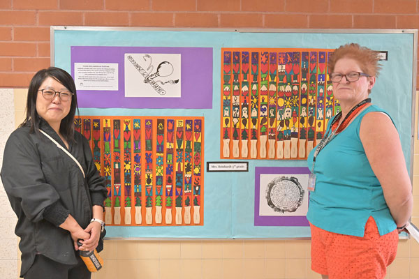 Teachers pose in from of art.