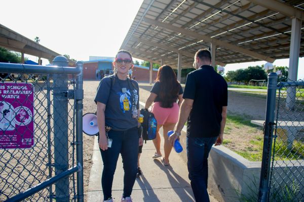 A woman smiles as she welcomes families into the school courtyard